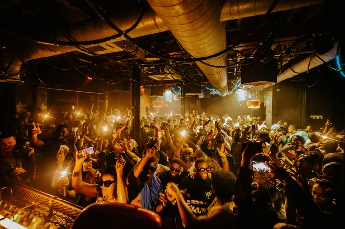 A packed dancefloor at XOYO under gold light, hands and phones in the air.